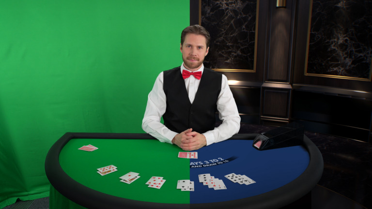 Male dealer at a blackjack table where half of the table and background is green screen.
